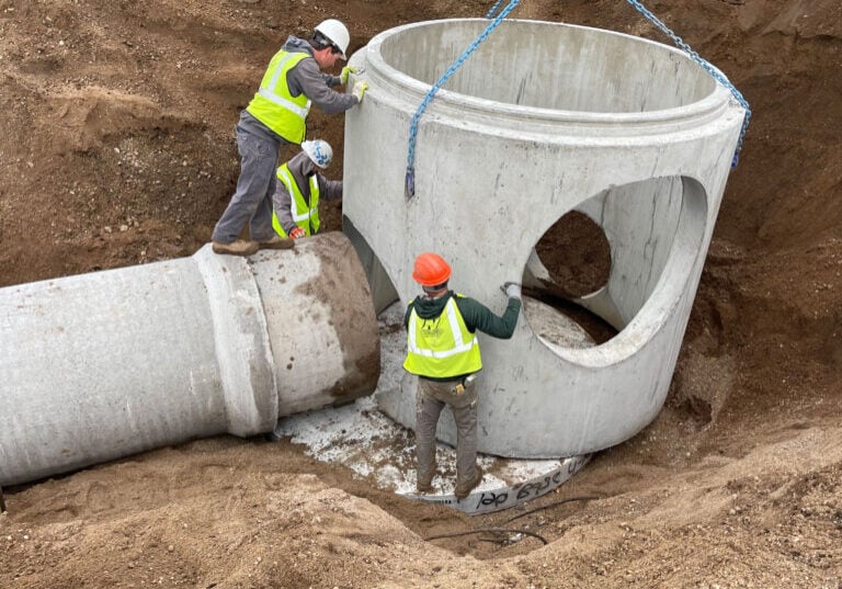 Nodland Construction employees placing sewer or water lines for a project.